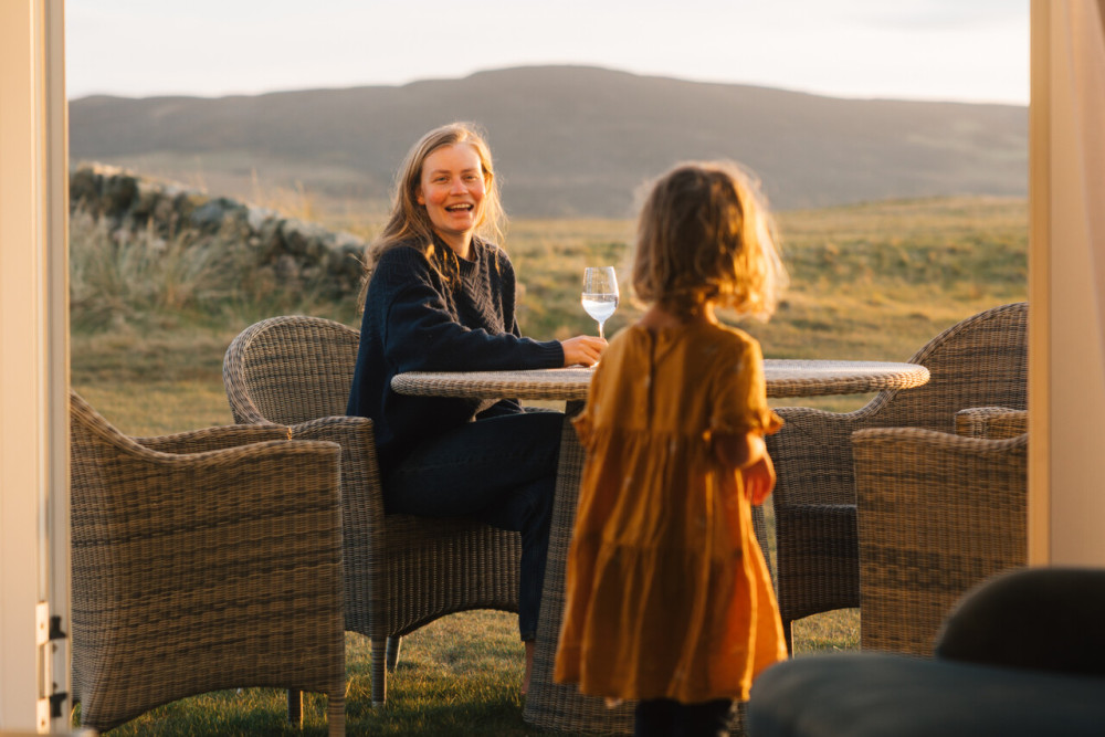 Mother and daughter sat outside their room at Another Place The Machrie on a summers evening