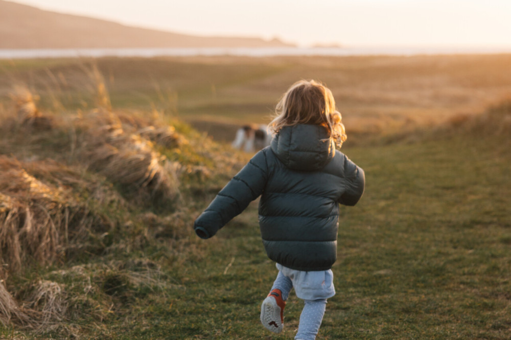 Little girl running alongside the golf course at Another Place, The Machrie